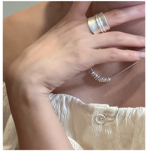 Macro shot of matte S925 sterling silver wide ring and spiral necklace on a model