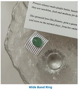 Macro detail of wide silver band ring with green agate stone on glass texture