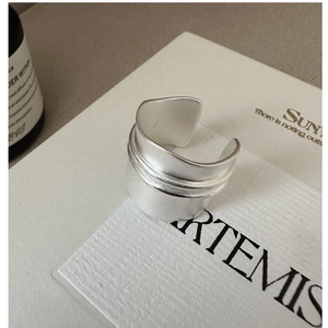 Detailed close-up of matte silver wide band ring with three-line embossed design