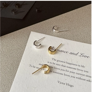 Detail of minimalist triple-layered C-shape stud earrings in gold and silver finish