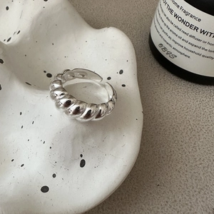 Minimalist S925 sterling silver croissant ring on a ceramic tray with soft lighting