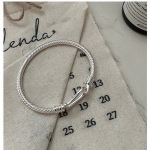 Close-up of S925 sterling silver horseshoe cable bracelet with hook clasp on canvas