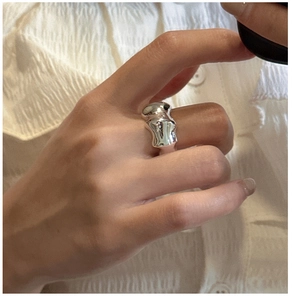 Close-up of a silver ring with an irregular organic texture on a female hand