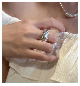 Detail of irregular liquid silver ring texture on finger with modern metallic finish