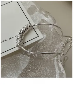 Macro detail of S925 sterling silver coiled pendant on a sleek snake chain necklace