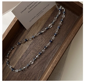 Détail du collier en argent S925 avec perles de cristal bleu sur un plateau en bois