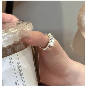 Detail of silver fluid lava ring with molten liquid metal design worn on thumb