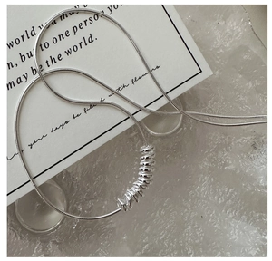 Macro shot of S925 sterling silver snake chain with multi-ring pendant on card