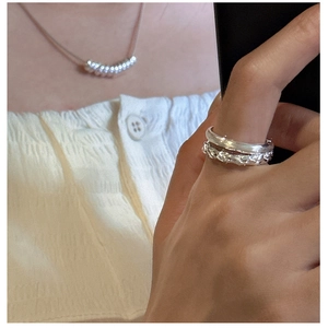 Dettaglio di anelli sovrapposti in argento sterling S925 con finitura a treccia e liscia