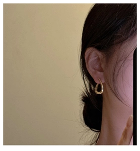 Detail of elegant gold irregular teardrop hoop earrings worn by a female model