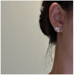 Detail of three-bead cluster pearl earrings in minimalist French style on model ear