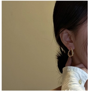 Close-up of a minimalist golden teardrop earring worn by a model for a modern look