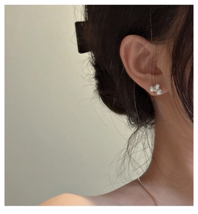 Close-up of S925 silver stud earrings with three clustered white pearls on earlobe