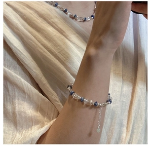 Détail du bracelet en argent S925 avec pierres bleues et pendentif cœur sur lin