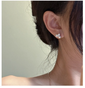 Close-up of minimalist S925 sterling silver stud earrings with three elegant white pearls
