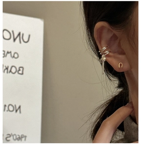 Detail von silberner Earcuff-Manschette und goldenem U-Ohrstecker am Ohr getragen