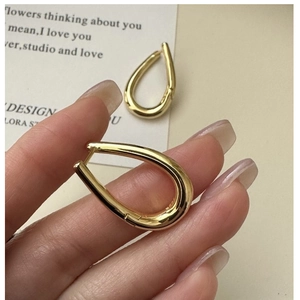 Macro shot of S925 hallmark on gold teardrop hoop earrings in a minimalist style