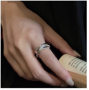 Detailed close-up of a silver multilayered twisted ring shown worn on a finger