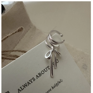 Detailansicht silberner Ohrmanschette mit Schleife und dreilagigem Ring auf Karte