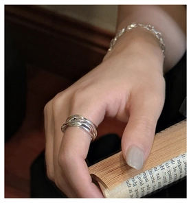 Detail of layered silver rings and minimalist chain bracelet on vintage book
