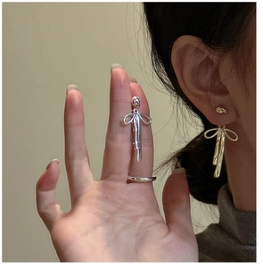 Detail of S925 sterling silver ribbon bow earrings and smooth metal ring set on model