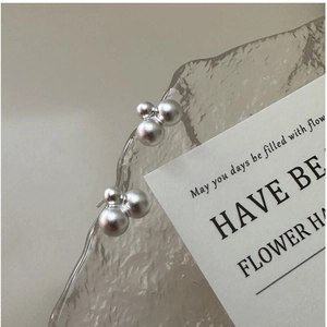 Detailed view of matte silver earrings with three connected graduated spheres on a tray