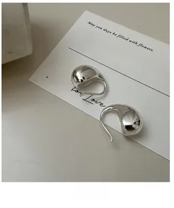 Macro shot of polished S925 sterling silver irregular teardrop earrings on white card