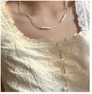Close-up of Baroque pearl necklace with gold beads worn on a lace collar dress