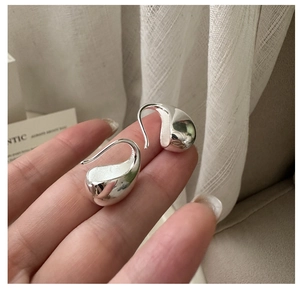 Detailed macro view of S925 sterling silver waterdrop earrings held on fingertips