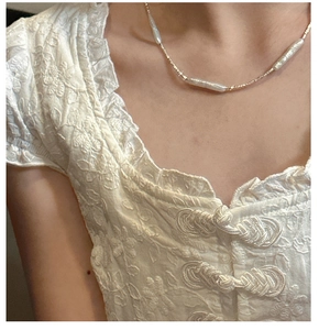 Close-up of baroque pearl necklace with golden beads on collarbone in vintage style