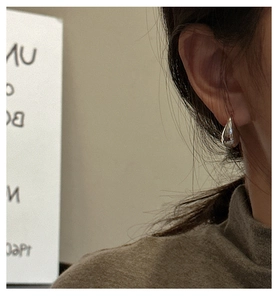 Detailed close-up of a silver teardrop earring featuring a high-polish mirror finish on a model
