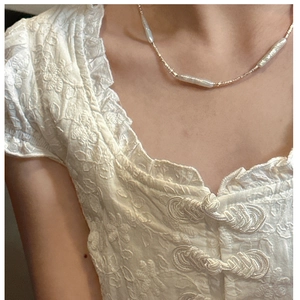 Detail of s925 silver necklace featuring baroque pearls and gold beads on a model