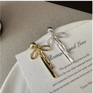 Macro shot of silver and gold textured bow earrings on a decorative paper card