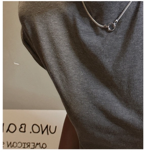 Detail of silver snake chain necklace with round crystal pendant on grey knitwear