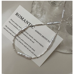 Detail of baroque pearl and silver bead necklace on elegant minimalist prop card