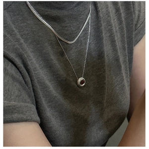Close-up of double-layered silver snake chain necklace with a red gemstone pendant