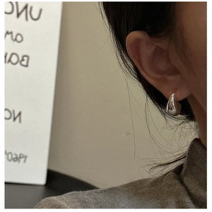 Close-up of polished S925 sterling silver teardrop earring on model with minimalist style