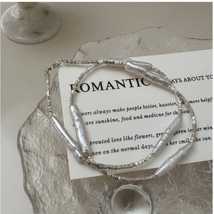 Detailed close-up of s925 silver beaded necklace with baroque pearls on glass tray