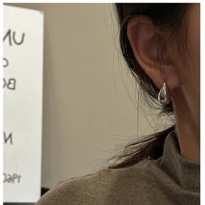 Detailed view of polished S925 sterling silver teardrop earrings worn by a model