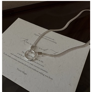 Close-up of S925 sterling silver snake chain necklace with circular clasp on paper