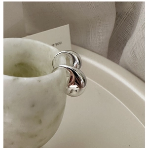 Close-up of S925 sterling silver liquid teardrop earring on marble surface textures