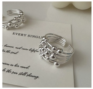 Macro detail of silver S925 multi-layered beaded open ring on a minimal card