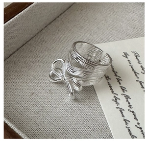 Macro shot of silver bow ring featuring detailed brushed metal texture and open band design