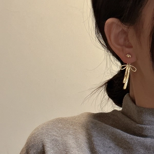 Elegant gold bow textured earrings on model made of polished S925 sterling silver