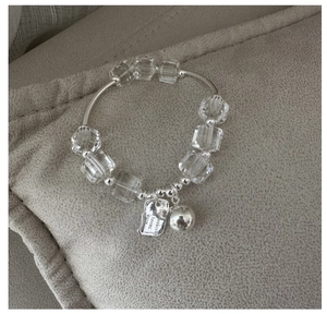 Macro shot of silver tube bracelet with clear geometric crystal beads and tiny bell charm