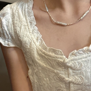 Baroque pearl necklace with gold beads on model wearing white embroidered shirt