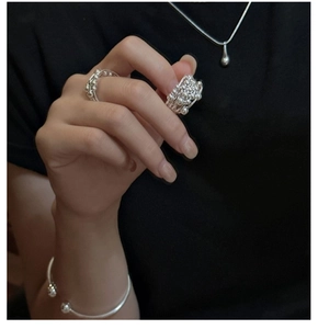 Detail of layered silver bead rings and minimalist teardrop necklace on model