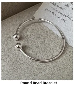 Makroaufnahme eines minimalistischen Silberarmreifs mit zwei Perlen auf grauem Grund