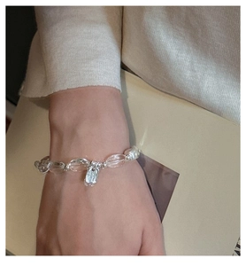 Detail of S925 silver bracelet featuring white crystals and pearls on a woman's wrist