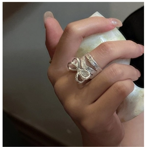 Close-up of a silver bow ring with multi-layered textured band worn on hand